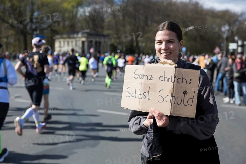 A person at the edge of the course holds a sign Honestly: it's your own fault at the 44th Generali Berlin Half Marathon 2025 in Berlin on 6 April 2025