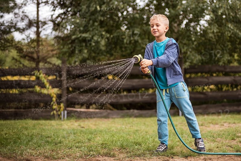 Young boy watering grass in the garden