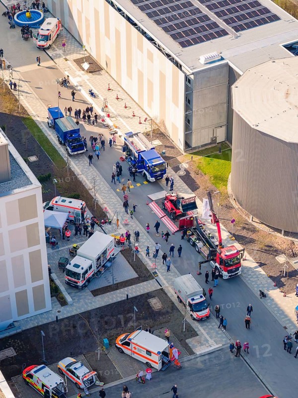 Aerial view of an emergency scene with fire engines and a crowd of people in a city, hospital opening, Calw, Germany