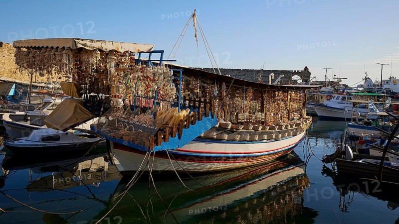 Boat in harbour loaded with souvenirs, reflected in calm water, harbour area, Rhodes Town, Rhodes, Dodecanese, Greek Islands, Greece