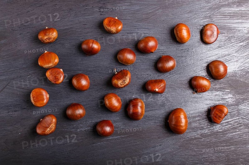 Pile of sweet chestnuts on black wooden background with copy space, top view