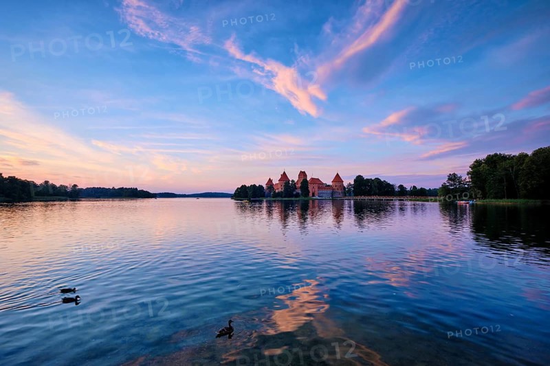 Trakai Island Castle in lake Galve, Lithuania on sunset with dramatic sky reflecting in water and ducks. Trakai Castle is one of major tourist attractions of Lituania