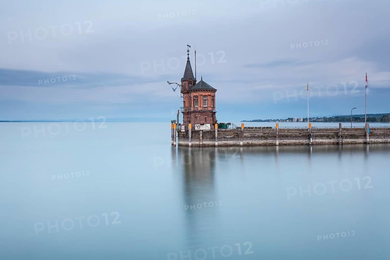 Long exposure of the historic gauge house at the harbor entrance on the smooth water surface of Lake Constance, Constance, Baden-Wuerttemberg, Germany