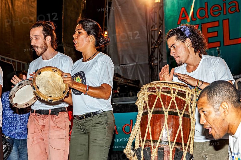 Three people passionately play drums and percussion instruments at a concert, a band plays and dances at a festival in Petrolina in Brazil