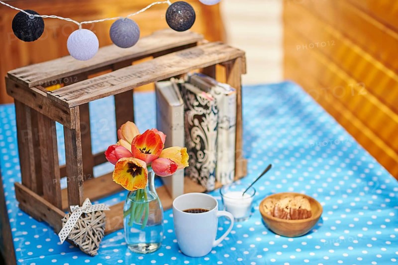 A cup of coffee, sugar, cookies and a vase of blossoms on a table, Germany