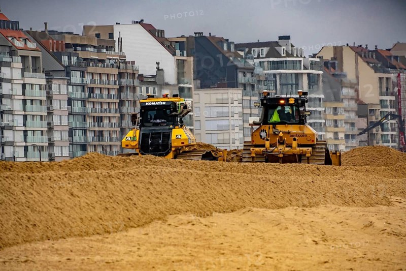 Bulldozers when distributing sand on the beach in the town of Knokke-Heist, part of coastal protection and beach maintenance, due to floods, erosion and sea level rise, the sand on the beach is repeatedly washed into the sea, in winter the sand from the seabed is washed back onto the beach with suction vessels, the excavators and levelers then distribute the sand back on the beach to eliminate the difference in height so as to bathe To make the beach usable again for the next season