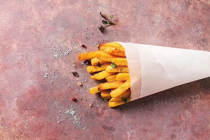 Fried French fries, in a paper bag, on an abstract background, no people, rustic