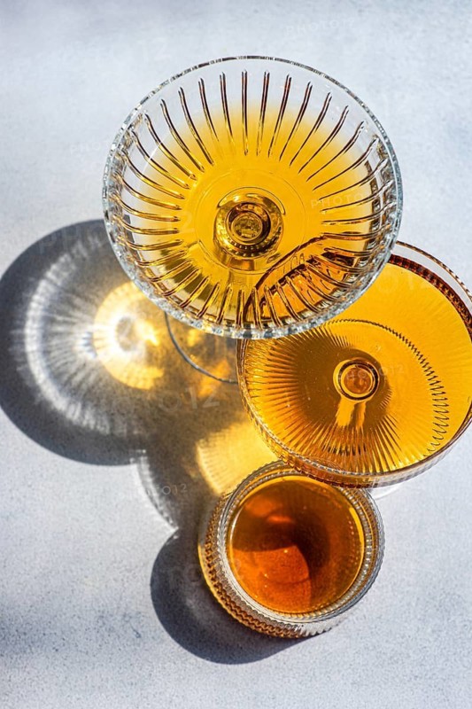 Elegant crystal glasses filled with Georgian amber wine, showcasing its rich hue and intricate glass design. Sunlight enhances the alluring golden tones and reflections