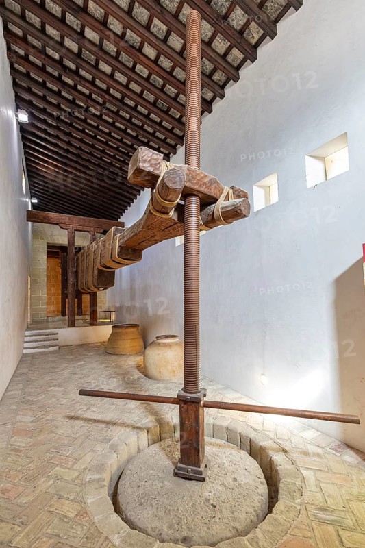 Antique wine press with solid wooden beams on a stone floor in a simple room, Jerez