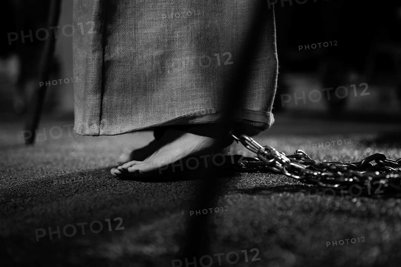 Black and white close up of feet shackled with a chain, representing penance in holy week. The image evokes emotions an tradition