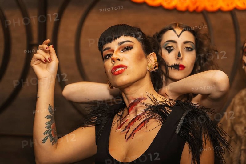 Female friends in costumes at the halloween party with friends in a disco nightclub
