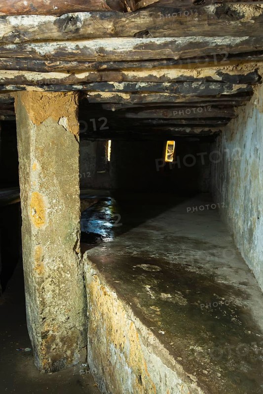 Interior of an underground slave holding chamber in Stone Town, Zanzibar. Low-angle view of cramped stone platforms and narrow air slits in a somber historic site