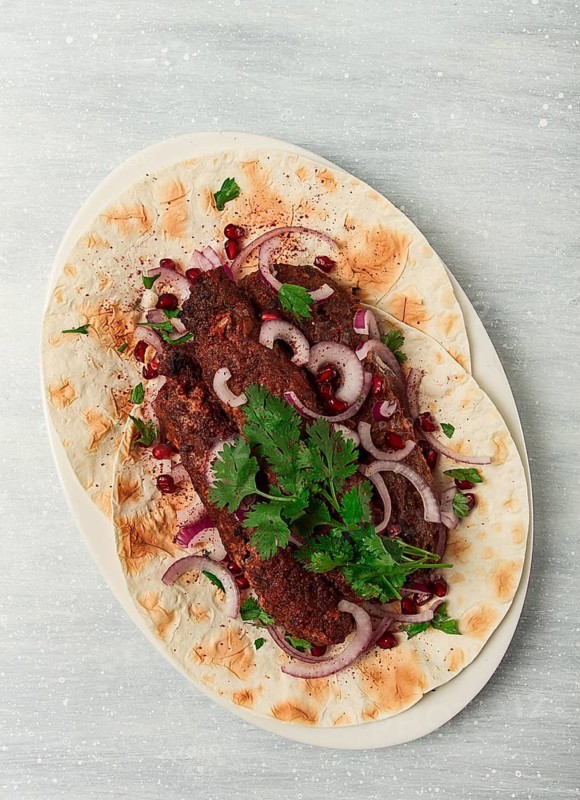 Lula kebab, on lavash, with red onion, pomegranate, and sumac, top view, close-up, horizontal, no people