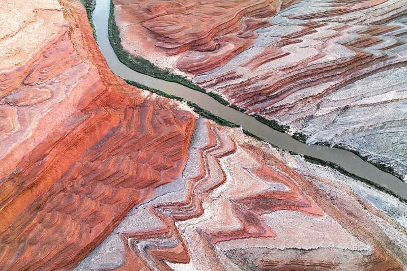 Captivating aerial shot of Rio San Juan weaving through the striking red and white geological formations in Utah, USA, showcasing nature's artwork from above