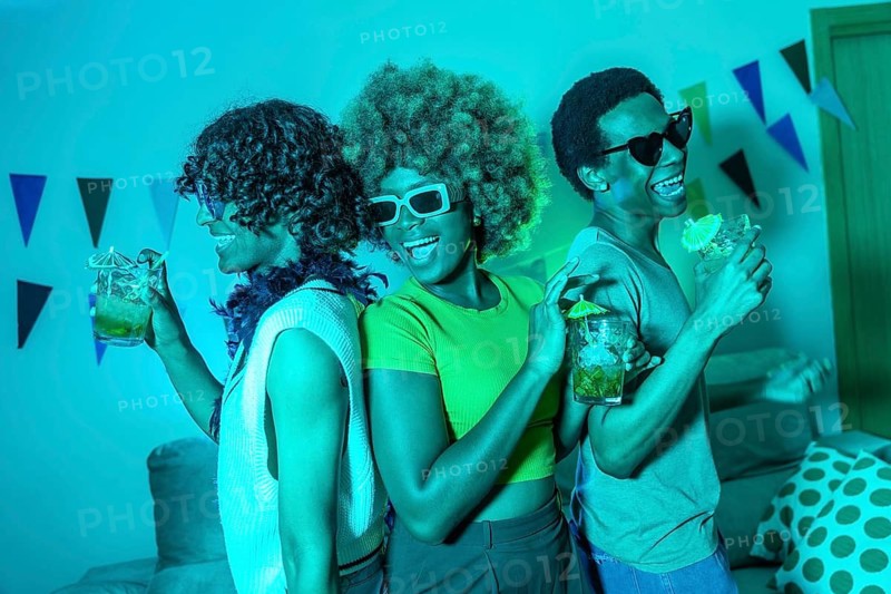 Happy multiracial friends dancing celebrating a party at home at night with colorful neon lights