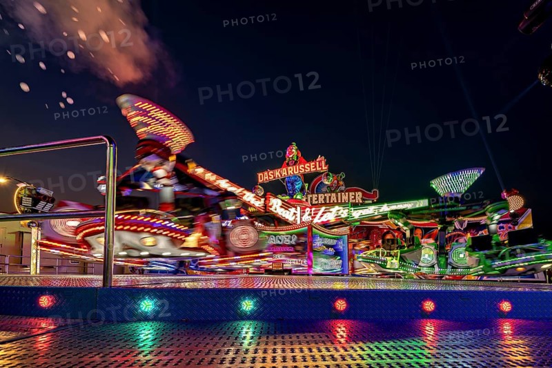 Glowing carousel in the lively atmosphere of a night-time fair, carousel and hustle and bustle of summer winnings in Eisenach