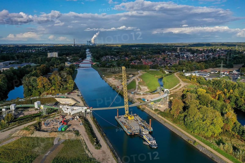 Castrop-Rauxel, North Rhine-Westphalia, Germany, new construction of a bridge -jump over the Emscher-, a floating crane on the Rhine-Herne Canal floating in the centre section of a foot and cycle bridge over the Emscher and the Rhine-Herne Canal. EMSCHERLAND construction project, a 37-hectare water and nature adventure park at the water crossroads of the Rhine-Herne Canal (right) and the renaturalised Emscher (from right to left) on the city boundary between Recklinghausen and Castrop-Rauxel. EMSCHERLAND will also be a garden of the future for the International Garden Exhibition 2027. Before the renaturalisation, the Emscher river system was an open, above-ground wastewater canal, mixed water canal with surface water and wastewater. The Uniper power plant Datteln 4 in the background