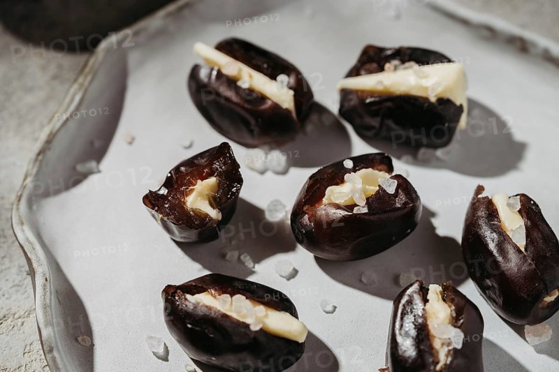 Close-up of plump dates stuffed with smooth butter and sprinkled with coarse sea salt. A delectable treat combining sweet and savory flavors, perfect for gourmet snacking