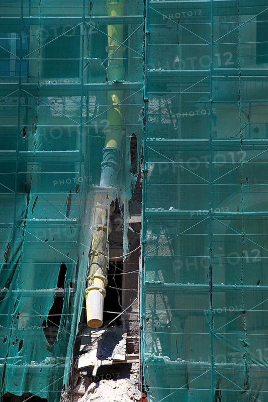 Construction site, house with scaffolding and a net in front of it as dust protection, waste tunnel for construction waste, renovation, renovation