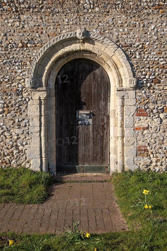 Chevron mouldings around doorway with weathered carved faces, Wantisden church, Suffolk, England, UK