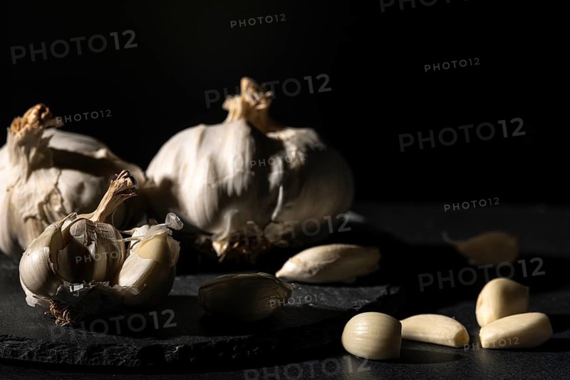 Garlic bulbs and cloves in dramatic lighting on dark background