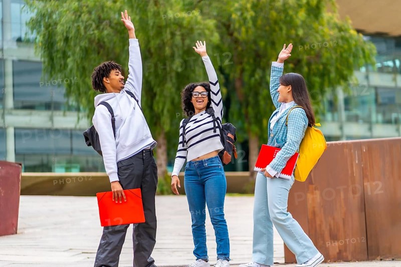 Multiracial group of friends gathering together stacking hands celebrating in the university campus