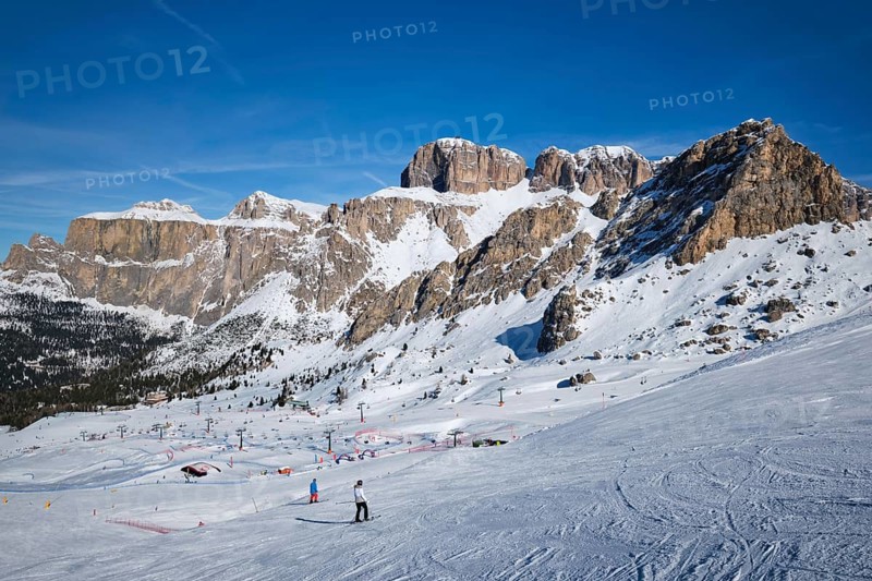 View of a ski resort piste with people skiing in Dolomites in Italy. Ski area Belvedere. Canazei, Italy