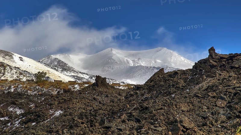 Black wall of lava rubble, blue sky, white clouds, snow-capped peaks, Etna, volcano, Eastern Sicily, Sicily, Italy