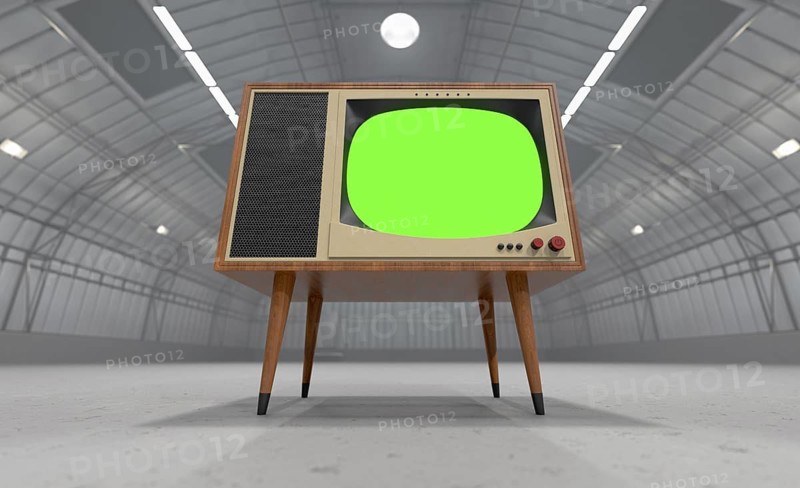 Vintage television with chroma green screen resting in the middle of an empty warehouse