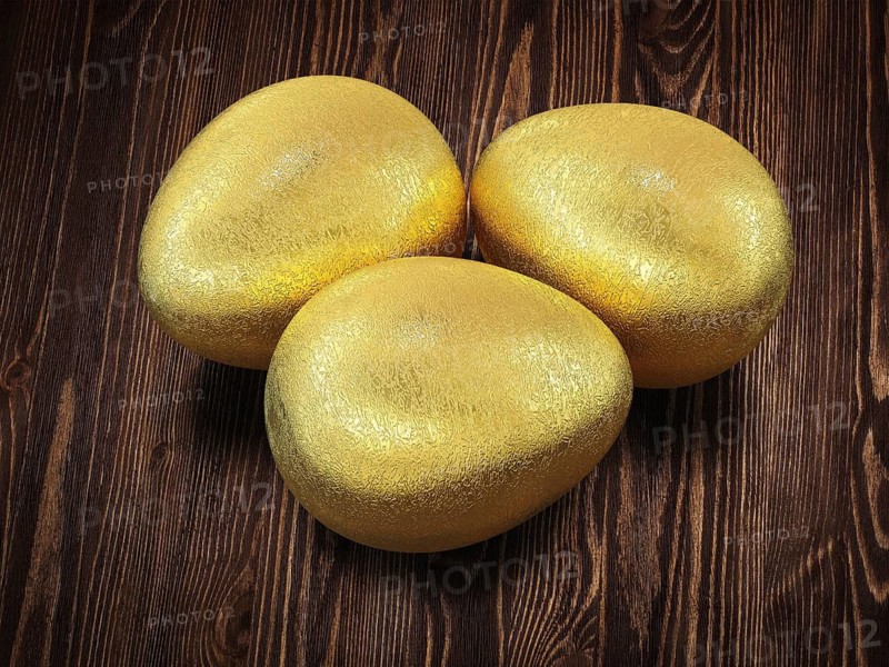 Three golden Easter eggs isolated on wooden background