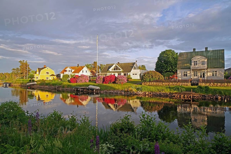 Picturesque house landscape reflected in the water, surrounded by blooming nature in spring, Göta Canal, Karlsborg, Västra Götalands län, Sweden