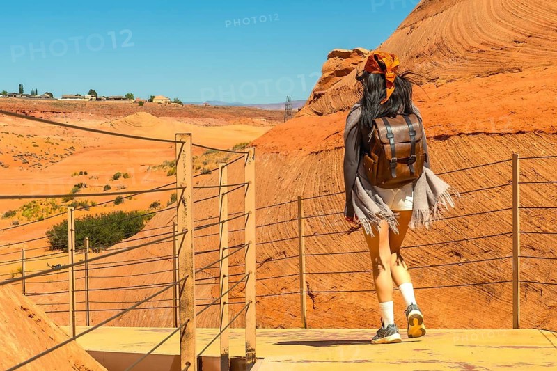 Woman hiking on a pathway carved into sandstone rock formations, experiencing adventure and travel through the scenic desert landscape of page, arizona