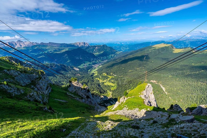 Cable car wires stretching across a breathtaking vista of the seceda mountain range in the dolomites, italy, during a vibrant summer day