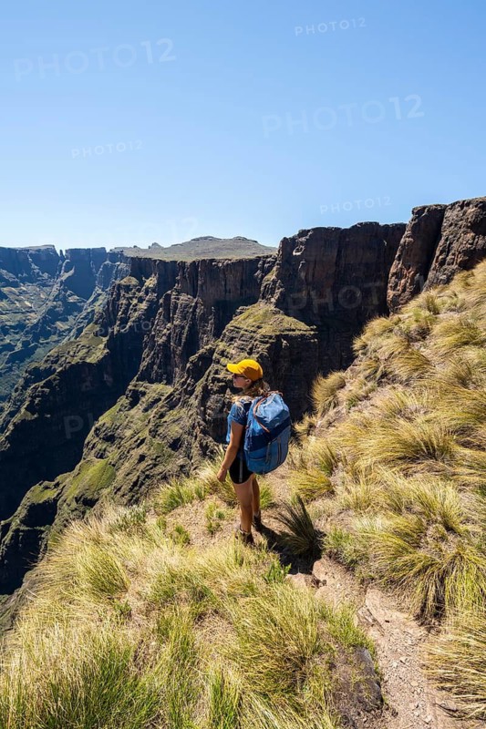 Young hiker looking at the impressive mountains and cliffs of the Drakensberg Mountains, hiking trail on the Sentinel Hiking Trail, Drakensberg, KwaZulu-Natal, South Africa
