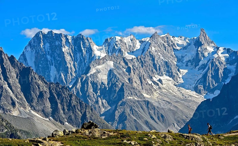 Hikers in the Aiguilles Rouges nature reserve in front of the mighty mountain range of the Grandes Jorasses, Chamonix, Haute Savoie, France