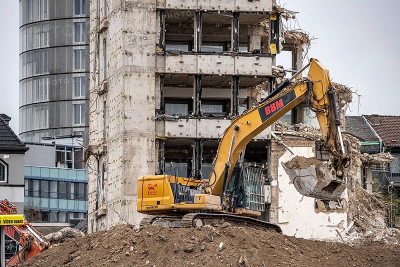Demolition of the former RWE building complex, in the city centre, on the A40 motorway in Essen, excavator working on the piles of rubble, in the background the RWE Tower, North Rhine-Westphalia, Germany