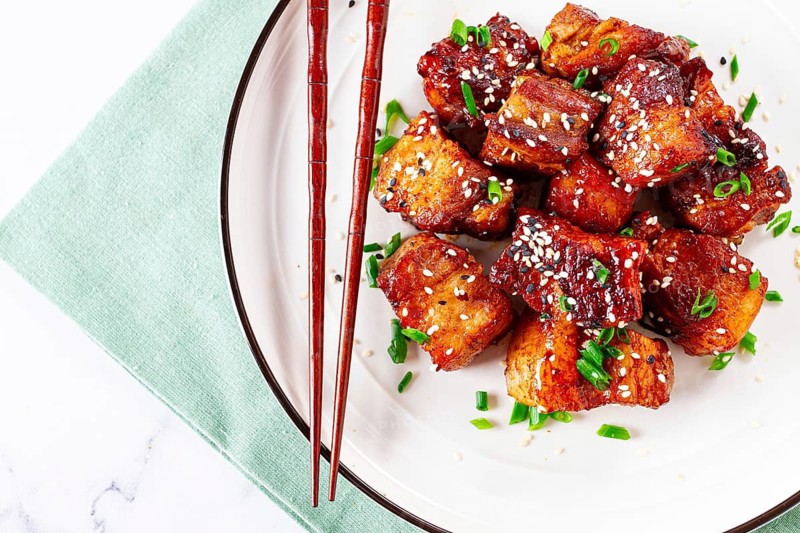 Chinese-style meat with sesame seeds and green onions, on a white plate, marble table, homemade, no people