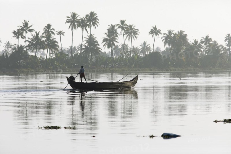 Fisherman in the morning with a boat on the Vembanad Lake, canal system of the backwaters, Kerala, India