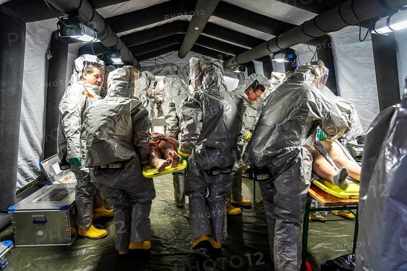 Decontamination of injured persons after an assumed accident involving hazardous substances, fire brigade and aid organisations practise setting up and operating a decontamination station, injured persons are sighted and then washed in a special shower tent to remove possible hazardous substances and chemicals in order to avoid further injuries, the emergency services wear special, ventilated protective suits, large-scale exercise by the Essen fire brigade