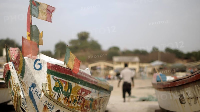 Colourful fishing boats with flags, Senegal flags in the foreground, a blurred man in the background, Cap Skirring, Casamance, Senegal