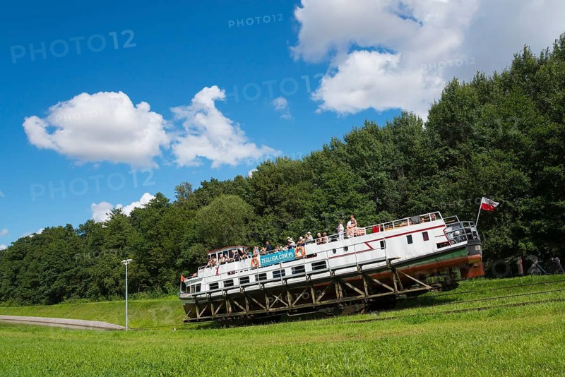 Boat with passengers on a railway carriage in front of a wooded backdrop in good weather, ship PingwinUpland Canal, Warminsko-Mazurskie, Poland, Upperland Canal, Elbling Osterode Canal, Elblag-Ostroda Canal, Warminsko-Mazurskie, Poland