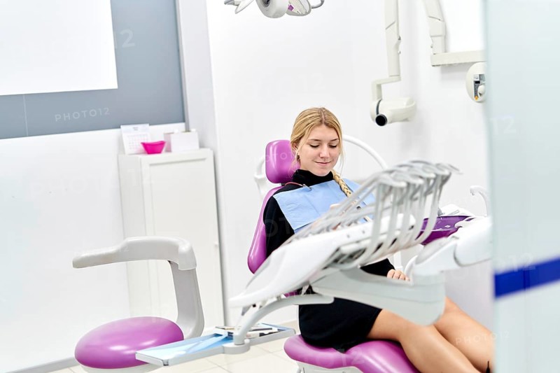 A patient sits comfortably in a modern dental clinic, preparing for a dental examination. The clinic features advanced equipment and a welcoming environment for dental care