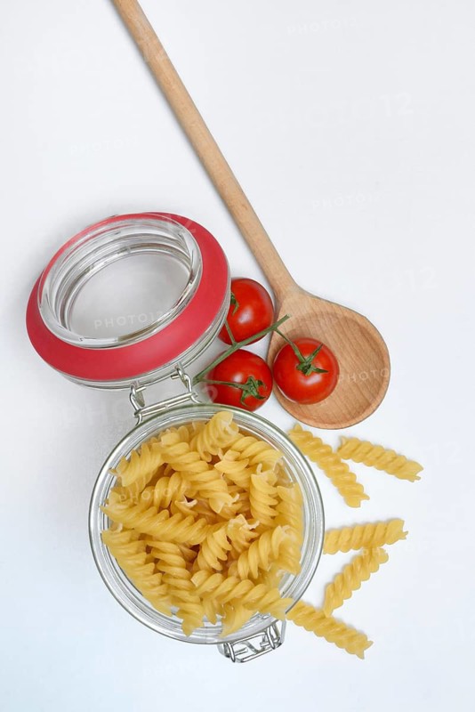 Pasta, 'Fusili' variety in glass container with cooking spoon