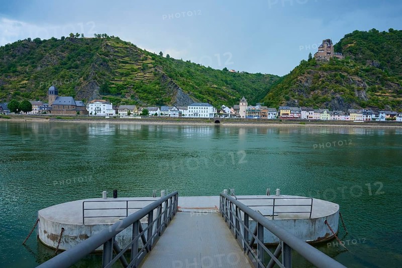 Boat dock on a river with a view of a village and Katz Castle on a hill, St. Goarhausen, Rhine, Rheingau, Hesse, Germany
