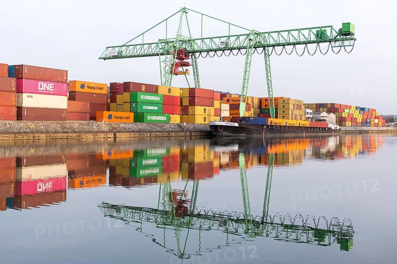 Colourful containers and a green crane are reflected in calm harbor water, Stuttgart, Baden-Württemberg, Germany