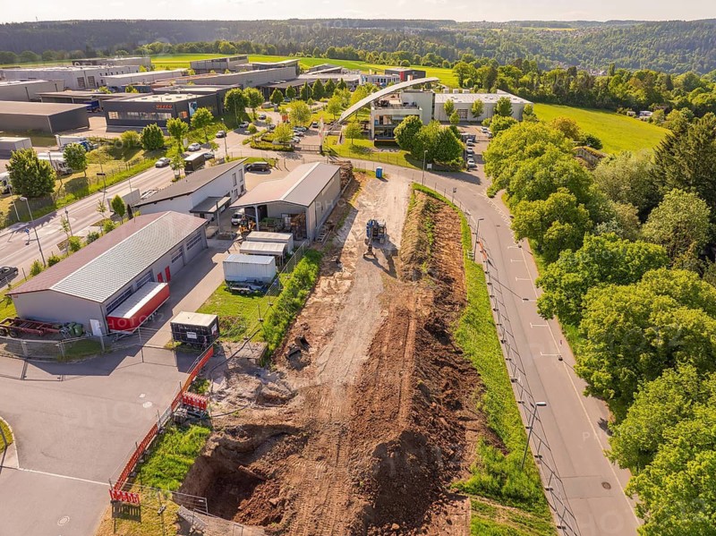 Earthworks along a road with green surroundings and urban development, Parkhaus Bau, Calw, Germany