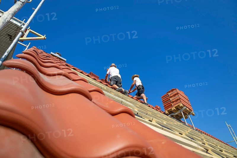 Roofers covering a tiled roof