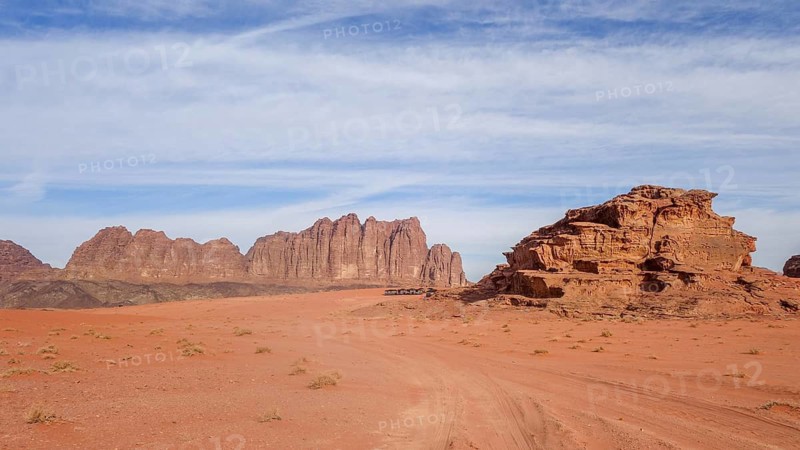 Expansive view of Wadi Rum's sandy desert and towering rock formations under a clear blue sky in Jordan, showcasing the natural beauty and serene vastness of the area