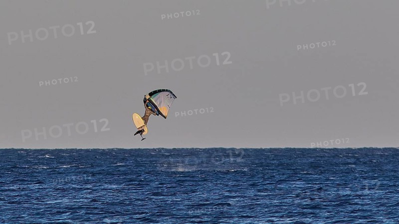Wingfoiller, A kitesurfer in the air over the blue sea, Windsurfer, Meltemi windsurfing spot, Devils Bay, Paralia Vatha, Vatha Beach, Southeast coast, Karpathos, Dodecanese, Greek Islands, Greece
