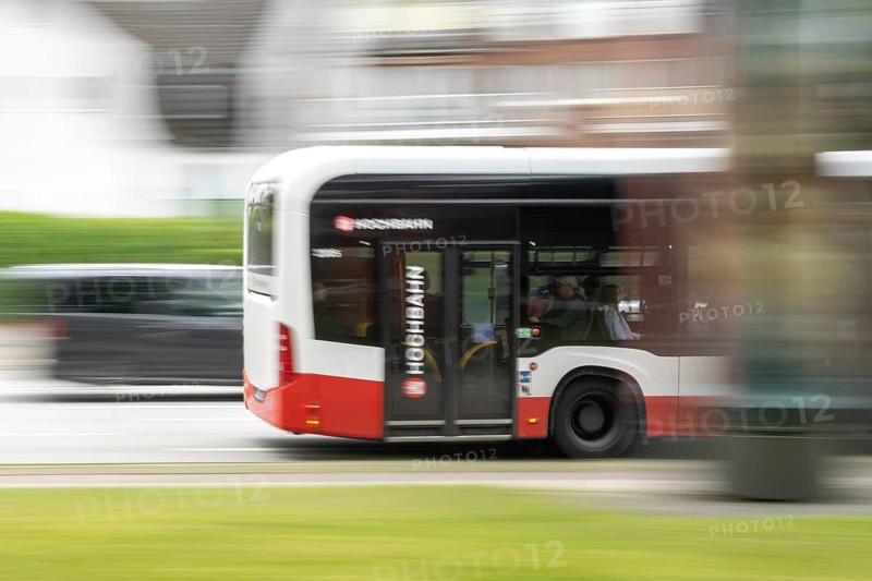 A Hamburg Hochbahn AG (HOCHBAHN) public service bus operating within the Hamburg Transport Association (HVV), captured as a panning shot with pronounced motion blur in traffic, Hamburg, Germany